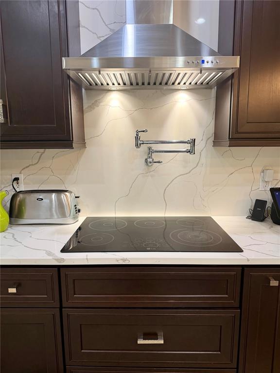 A kitchen features dark wood cabinets, a marble-patterned backsplash, and a stainless steel range hood — 1584 SHADOWMOSS CIRCLE, LAKE MARY, FL