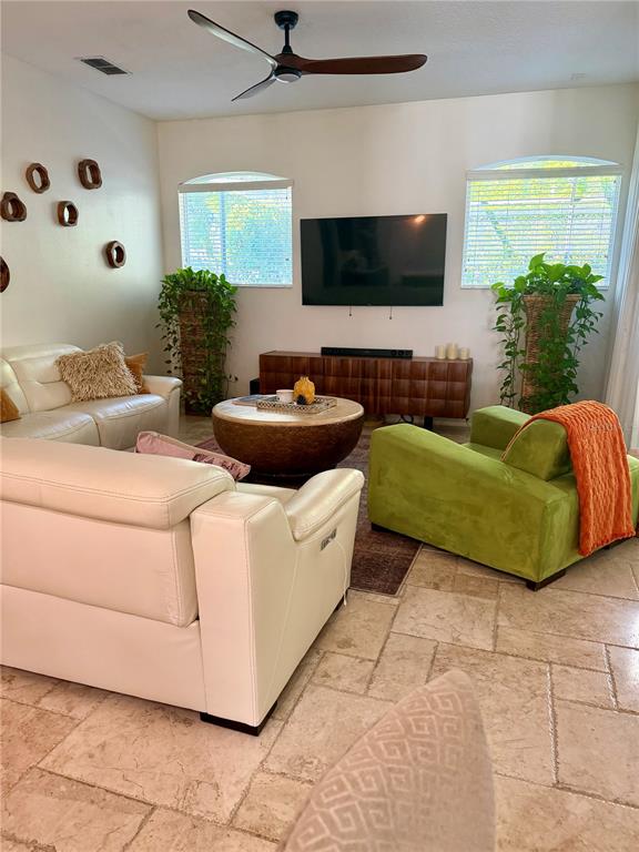A living room features a white sofa, a green armchair, and a television on a console — 1584 SHADOWMOSS CIRCLE, LAKE MARY, FL