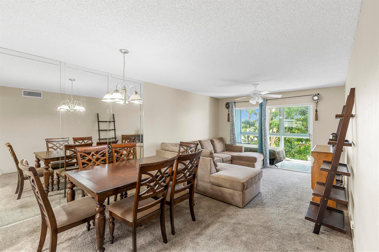 A living and dining area features a wooden table, sectional sofa, and mirrored wall — SUNRISE, FL