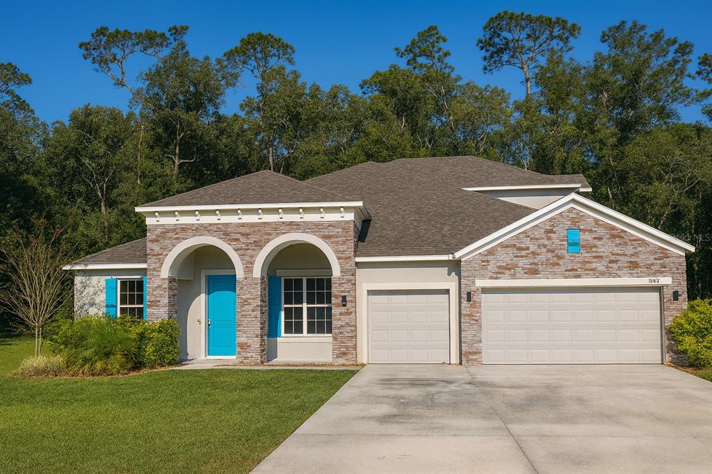 A single-story house features a stone facade, a bright blue door, and a three-car garage — 26047 EXMOOR DRIVE, SORRENTO, FL