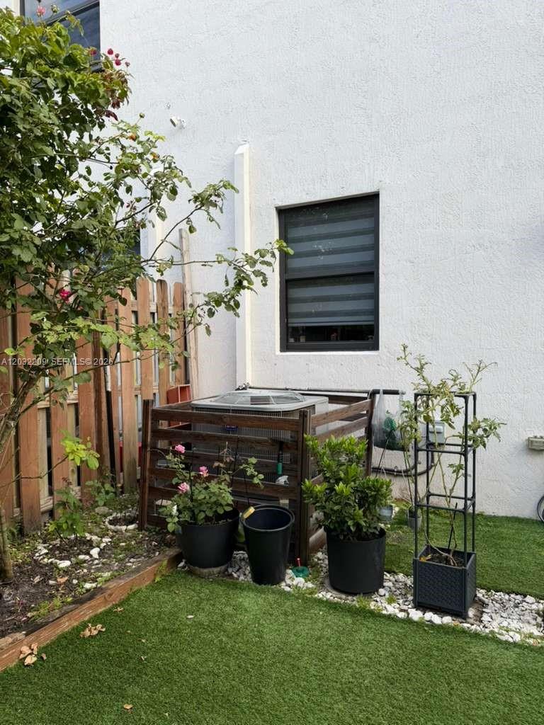 An outdoor area features an air conditioning unit enclosed by a wooden fence near plants — 20731 NE 7th Pl # 20731, Miami FL 33179, MIAMI, FL