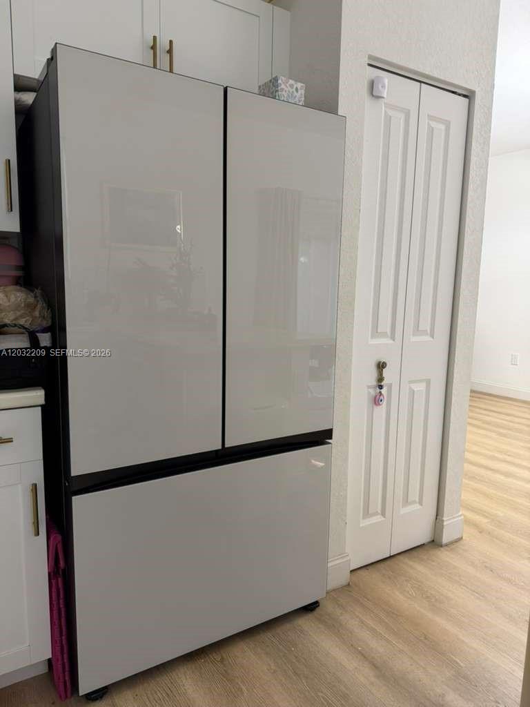 A modern, light-gray French door refrigerator stands in a kitchen next to a white door — 20731 NE 7th Pl # 20731, Miami FL 33179, MIAMI, FL