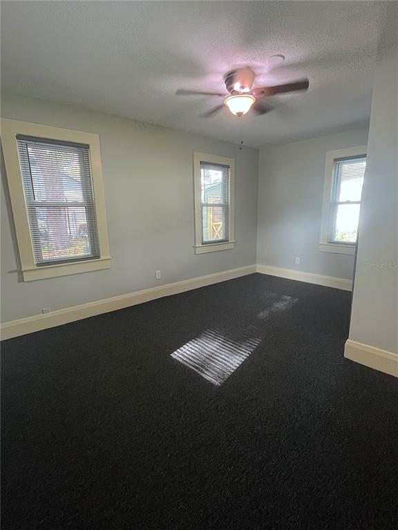 A bedroom with light blue walls, dark carpeting, three windows, and a ceiling fan — 402 W PARIS STREET, TAMPA, FL