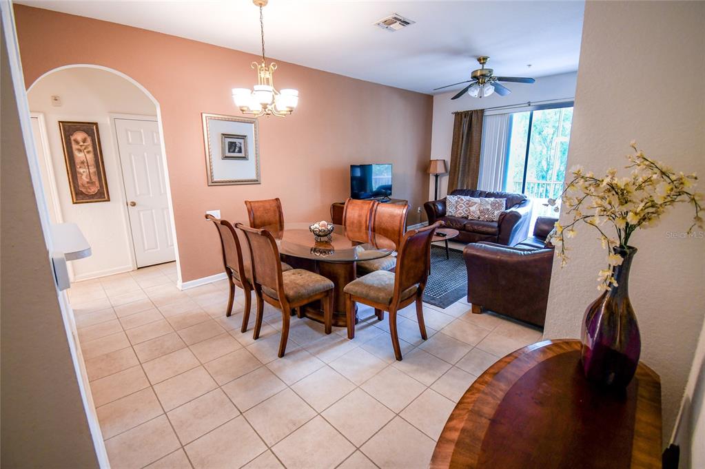 An open-concept dining and living area features tile flooring, a glass table, and leather furniture — 2788 ALMATON LOOP UNIT 202, KISSIMMEE, FL