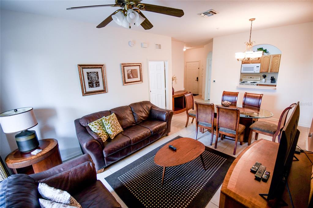 A living and dining area features brown leather furniture, a glass table, and tile flooring — 2788 ALMATON LOOP UNIT 202, KISSIMMEE, FL