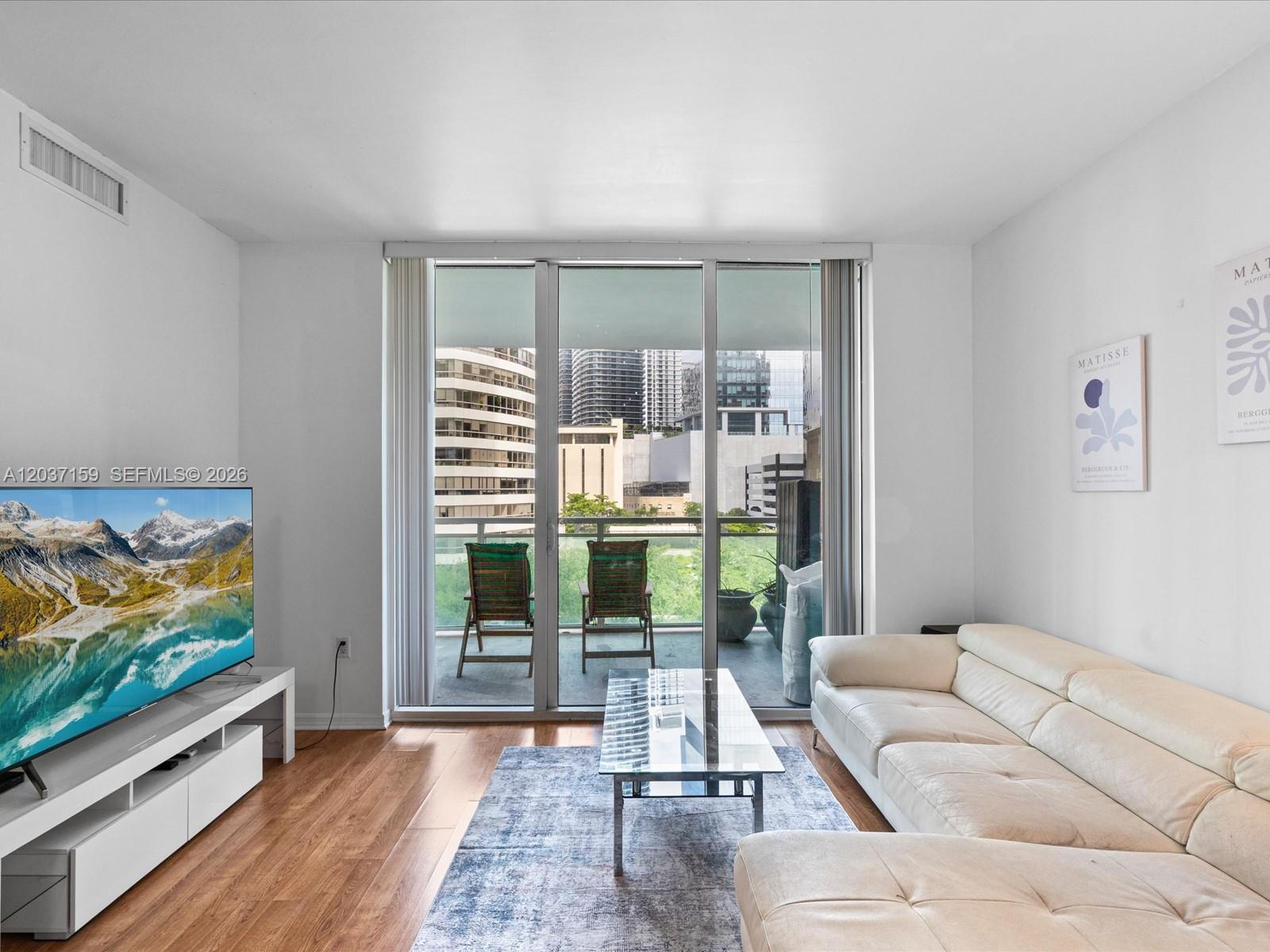A living room features a white sectional sofa, glass coffee table, and balcony with city views — 950 Brickell Bay Dr # 501, Miami FL 33131, MIAMI, FL
