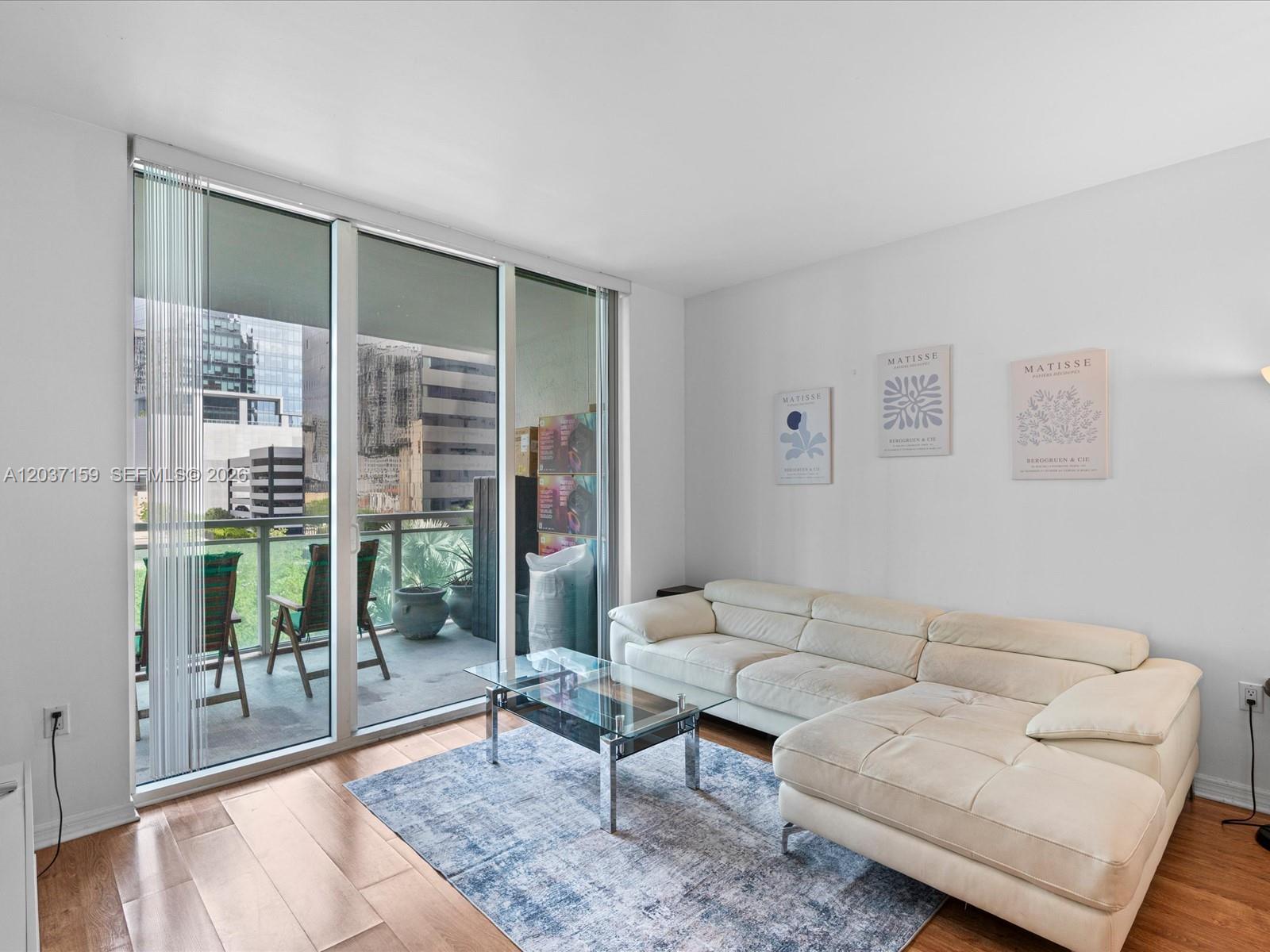 A living room features a white sectional sofa, glass coffee table, and a balcony view — 950 Brickell Bay Dr # 501, Miami FL 33131, MIAMI, FL