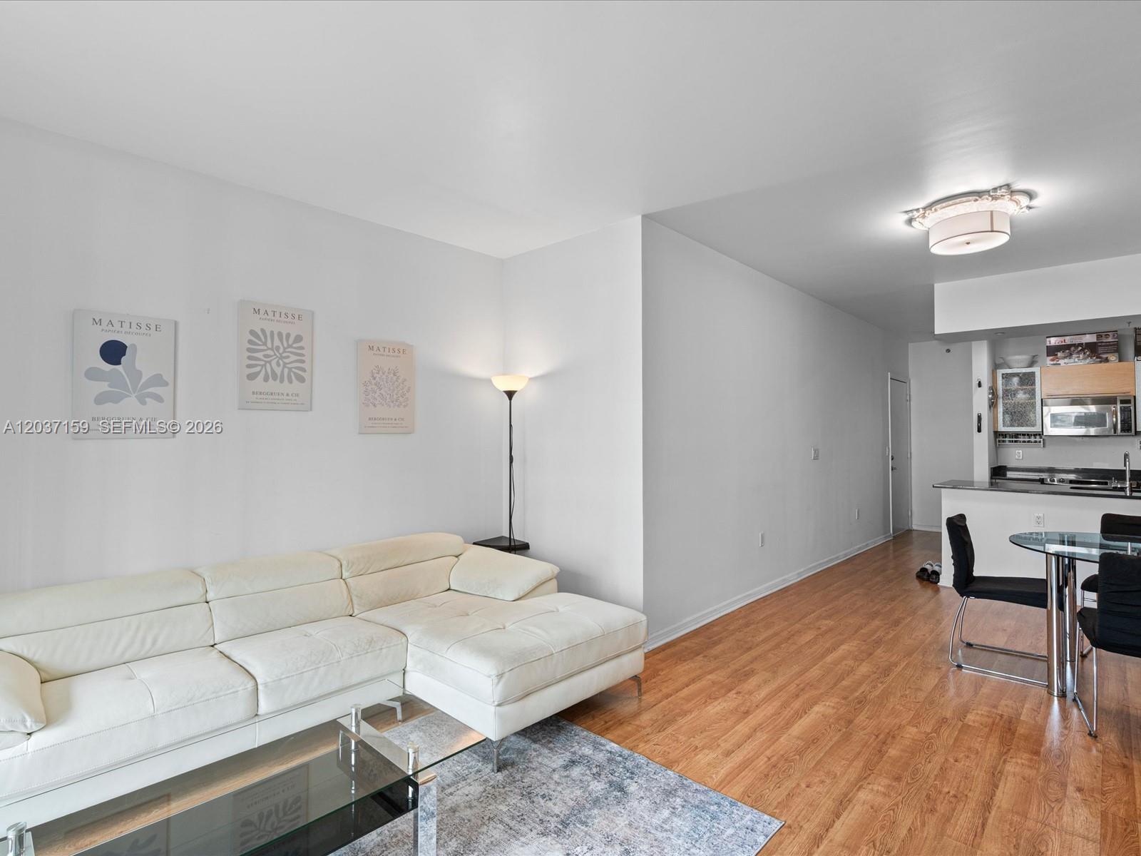 A living room with a white sectional sofa, Matisse wall art, and an adjacent kitchen — 950 Brickell Bay Dr # 501, Miami FL 33131, MIAMI, FL