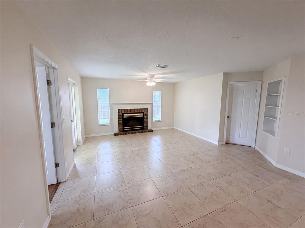 A living room features beige tile flooring, a fireplace, and built-in shelving — 1015 DEER RUN DRIVE, MELBOURNE, FL