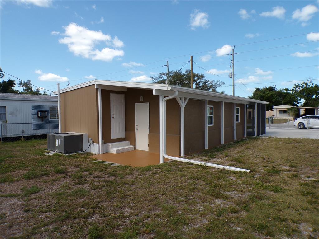 An exterior view of a tan mobile home with a small covered porch and gutters — 206 RAVENNA STREET N, NOKOMIS, FL