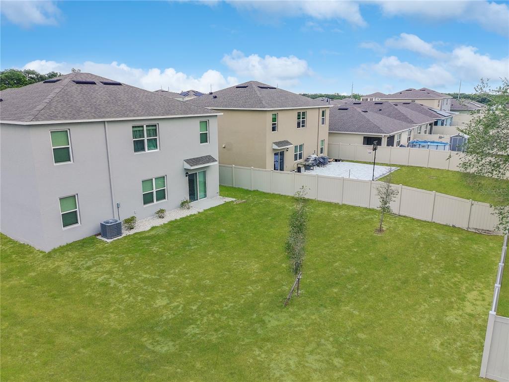 An aerial view shows the backyards of two suburban houses separated by a vinyl fence — 2085 DOE RUN DRIVE, DAVENPORT, FL