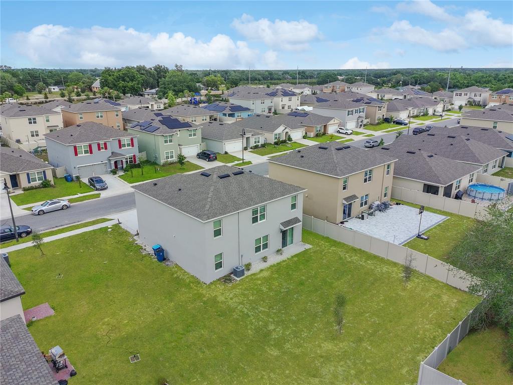 An aerial view shows a two-story suburban house with a large backyard and fence — 2085 DOE RUN DRIVE, DAVENPORT, FL
