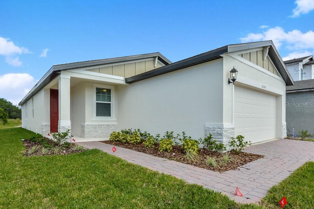 A single-story house with a white stucco facade, stone accents, and a two-car garage — 5247 MEREDREW LANE, ST CLOUD, FL