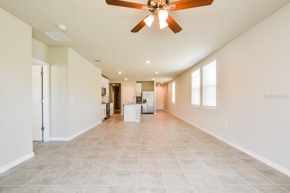 An open-concept kitchen and living area features tile flooring, recessed lighting, and a ceiling fan — 5247 MEREDREW LANE, ST CLOUD, FL