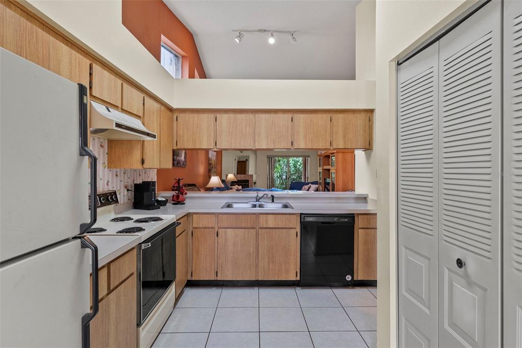 A view from a hallway into a kitchen with a breakfast bar and wooden stools — 8601 TWIN FARMS PL, TAMPA, FL