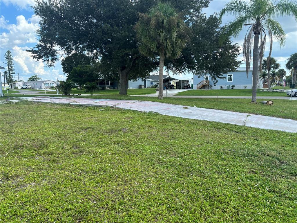 A vacant grassy lot features a concrete driveway slab under a clear blue sky — 1533 BLUE HERON DRIVE, ENGLEWOOD, FL