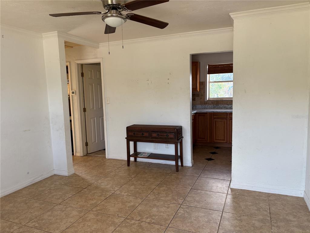 A room with tile flooring, a ceiling fan, a wooden console table, and a kitchen doorway — 6129 FREEMONT STREET, NORTH PORT, FL