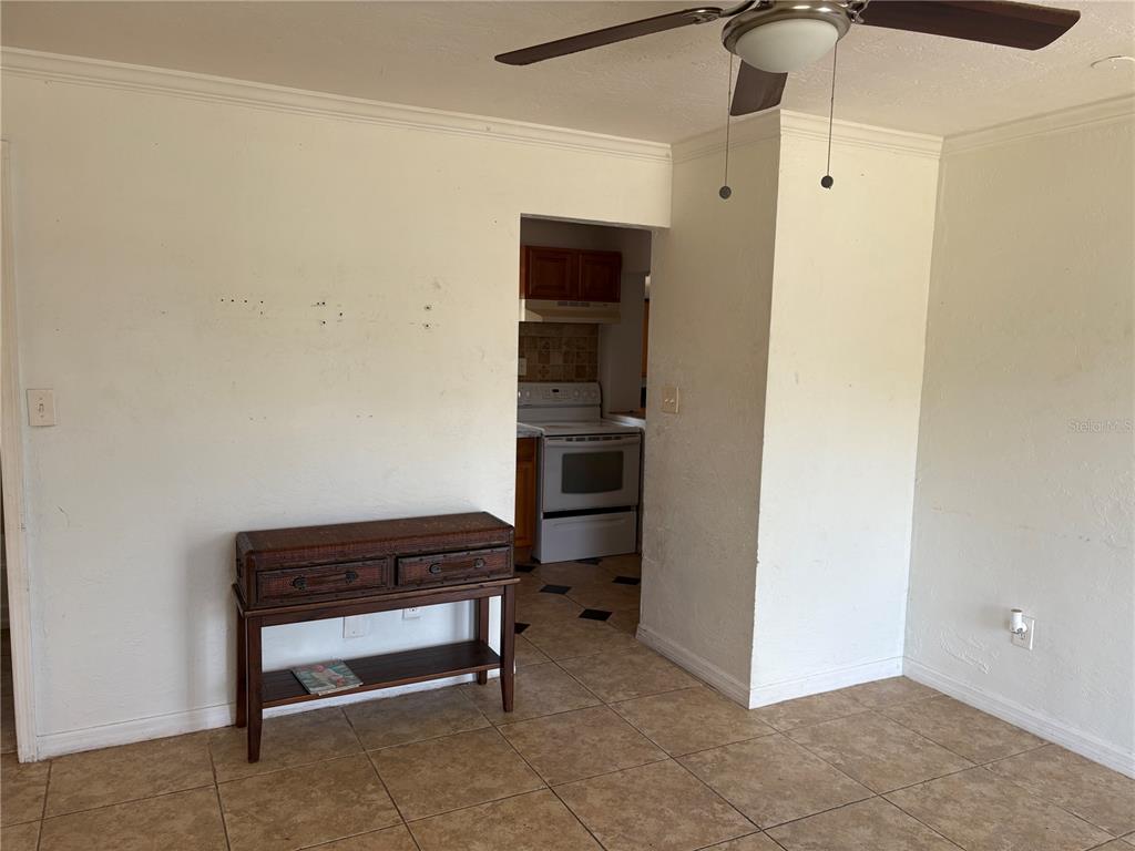 A room with tan tile flooring, a wooden console table, and a view into the kitchen — 6129 FREEMONT STREET, NORTH PORT, FL
