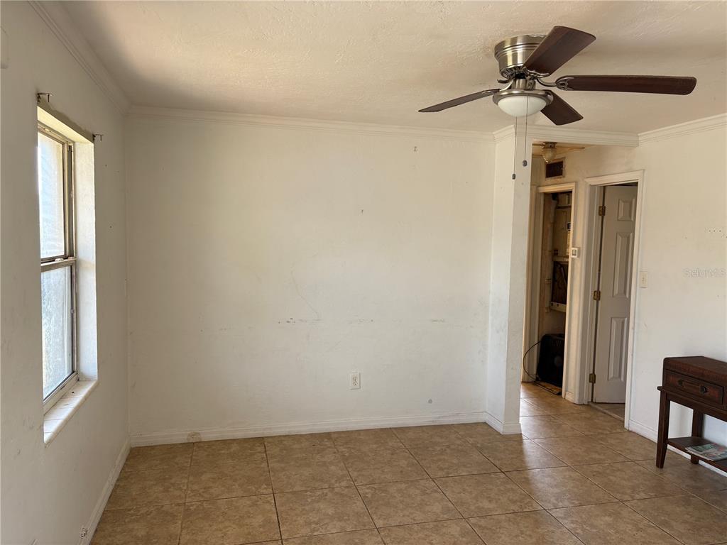 An empty room with beige tile flooring, a ceiling fan, and a window — 6129 FREEMONT STREET, NORTH PORT, FL