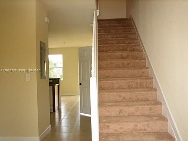 A carpeted staircase leads upward next to a hallway with tile flooring and a doorway — 9011 SW 227th St # 2, Cutler Bay FL 33190, CUTLER BAY, FL