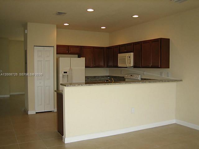 A kitchen features dark wood cabinets, granite countertops, and a white refrigerator — 9011 SW 227th St # 2, Cutler Bay FL 33190, CUTLER BAY, FL
