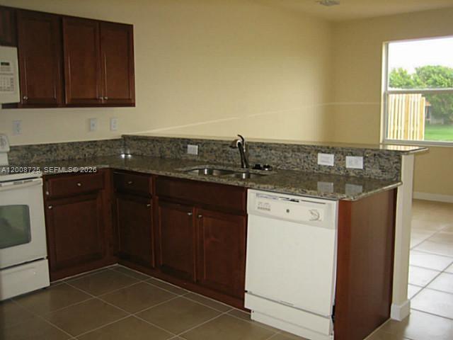 A kitchen features dark wood cabinets, granite countertops, a white dishwasher, and a white stove — 9011 SW 227th St # 2, Cutler Bay FL 33190, CUTLER BAY, FL
