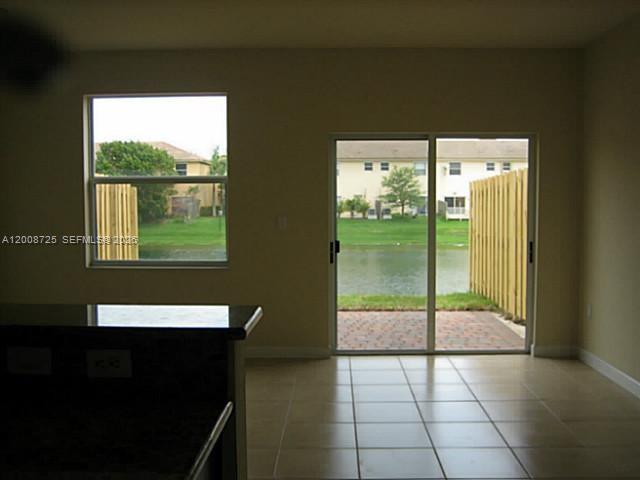 A room with tile flooring, a kitchen counter, and sliding glass doors overlooking a lake — 9011 SW 227th St # 2, Cutler Bay FL 33190, CUTLER BAY, FL