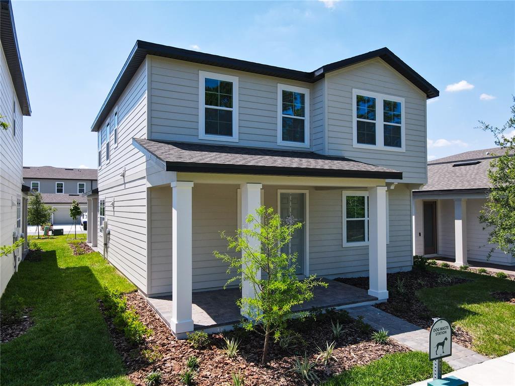 A two-story house with light-colored siding, a covered front porch, and a side air conditioner — 11165 GREEN CITRON ALLEY, WINTER GARDEN, FL
