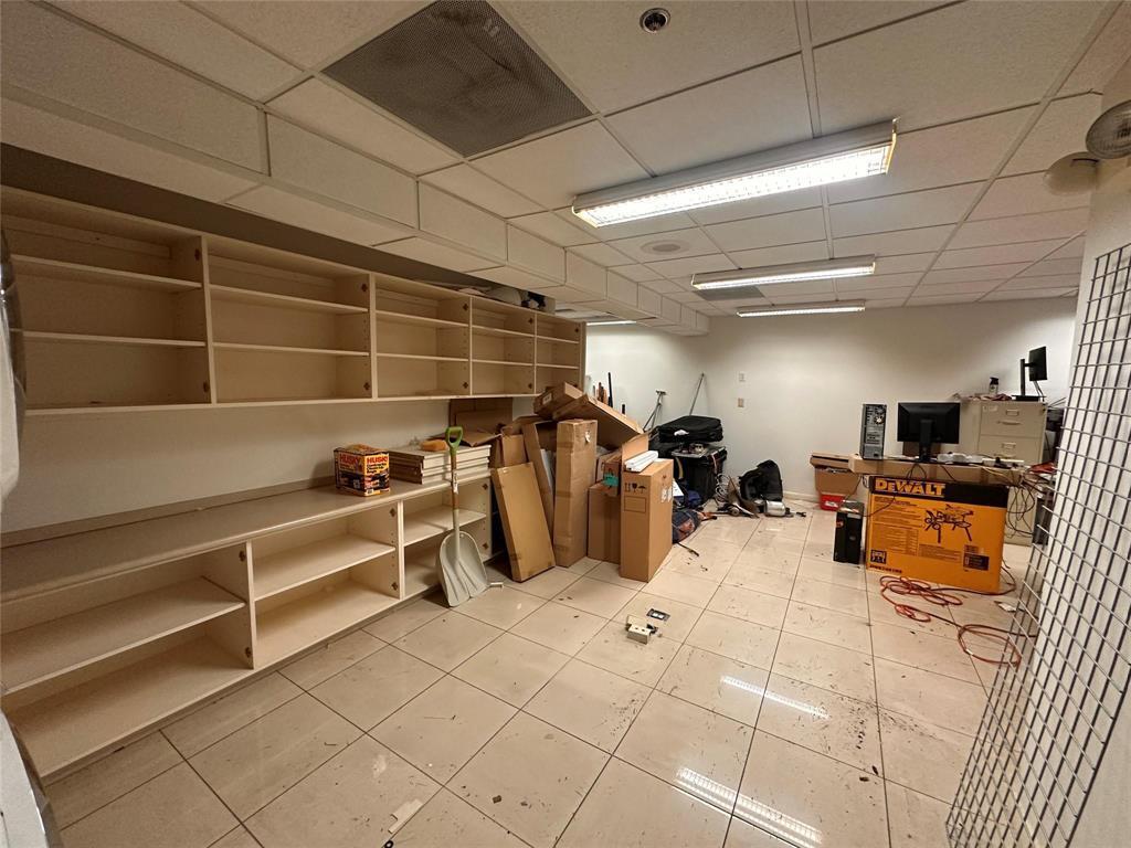 A storage room with white tiled floors, built-in shelving, and fluorescent ceiling lights — 1800 N Powerline Road # 11, Pompano Beach FL 33069, POMPANO BEACH, FL