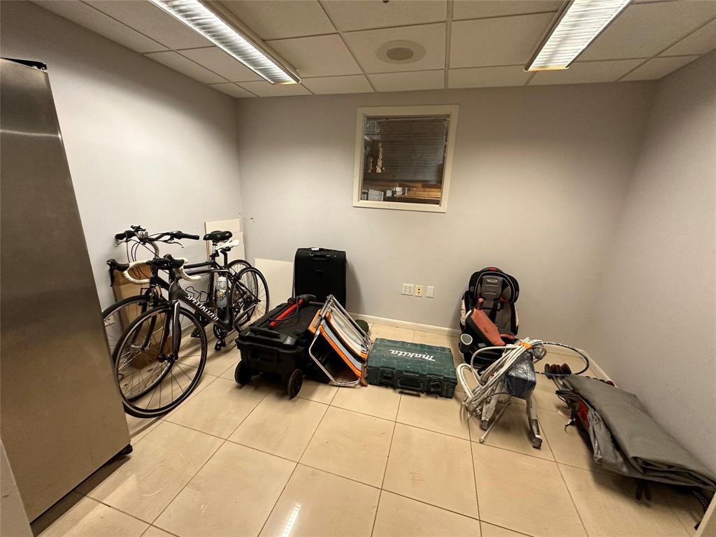 A room with light-colored tile flooring, a drop ceiling, and various stored items — 1800 N Powerline Road # 11, Pompano Beach FL 33069, POMPANO BEACH, FL