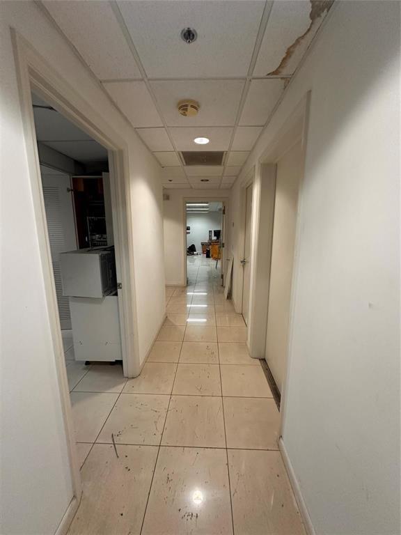 A narrow hallway with white walls, tiled floors, and a drop ceiling with water damage — 1800 N Powerline Road # 11, Pompano Beach FL 33069, POMPANO BEACH, FL