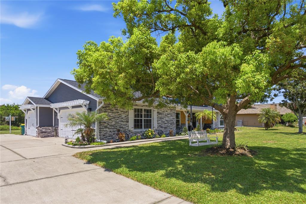 A single-story house with a stone facade, blue siding, and a large tree in front — 242 ANNALISA PLACE, MERRITT ISLAND, FL