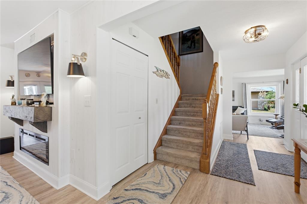 An entryway features a carpeted staircase, a fireplace with a mantel, and light wood flooring — 242 ANNALISA PLACE, MERRITT ISLAND, FL