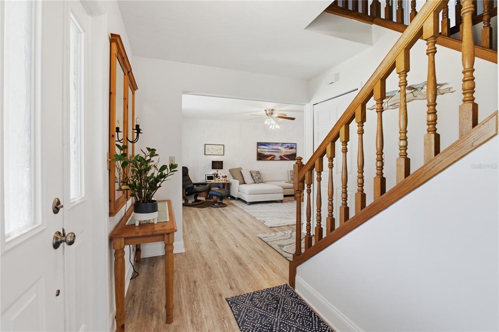 An entryway features light wood flooring, a wooden staircase with railings, and a console table — 242 ANNALISA PLACE, MERRITT ISLAND, FL