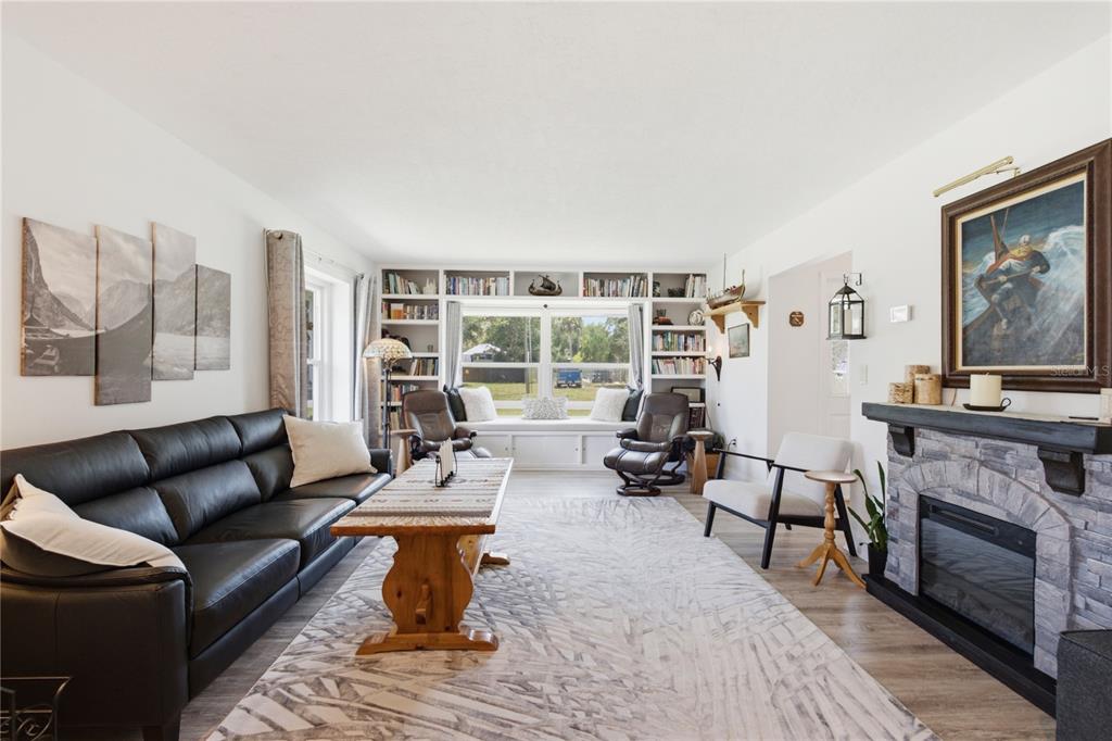 A living room features a stone fireplace, built-in bookshelves, a window seat, and leather furniture — 242 ANNALISA PLACE, MERRITT ISLAND, FL
