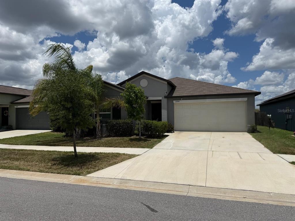 A residential street view showing houses, sidewalks, and tire marks on the asphalt road — 13204 GREAT PLAINS DRIVE, RIVERVIEW, FL