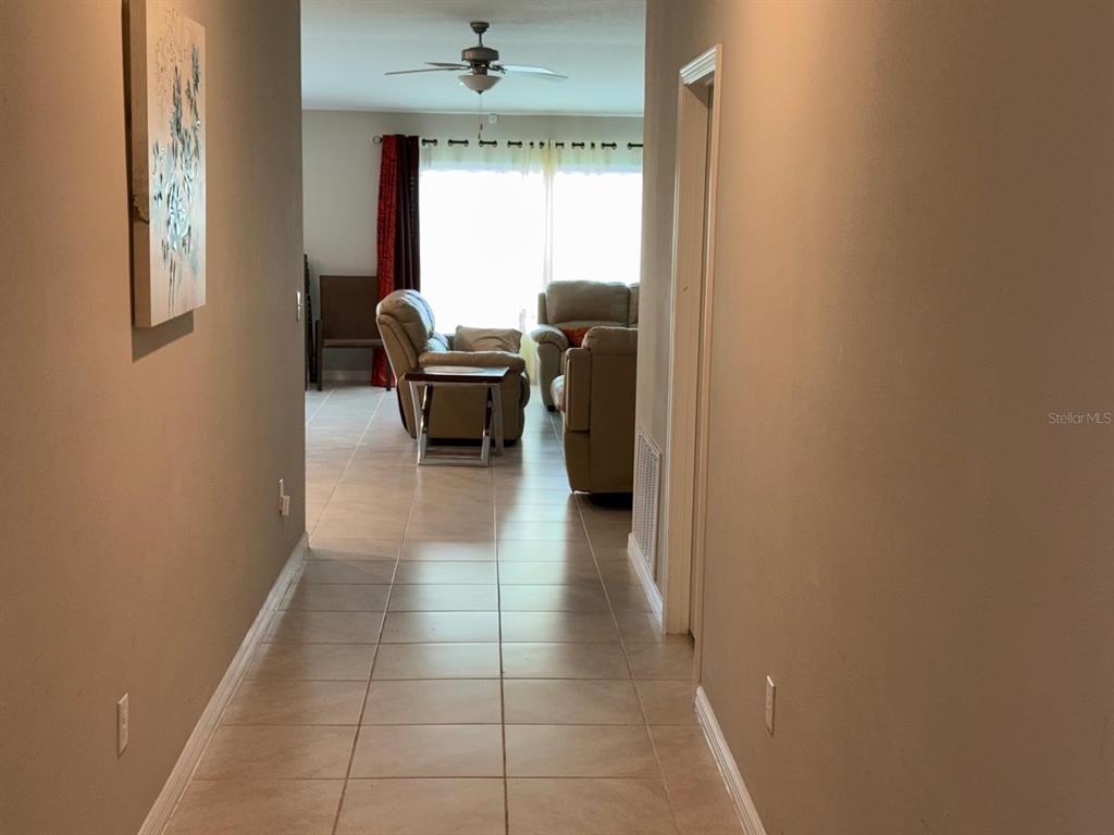 A living room features light-colored tile flooring, two beige sofas, a television, and a coffee table — 13204 GREAT PLAINS DRIVE, RIVERVIEW, FL