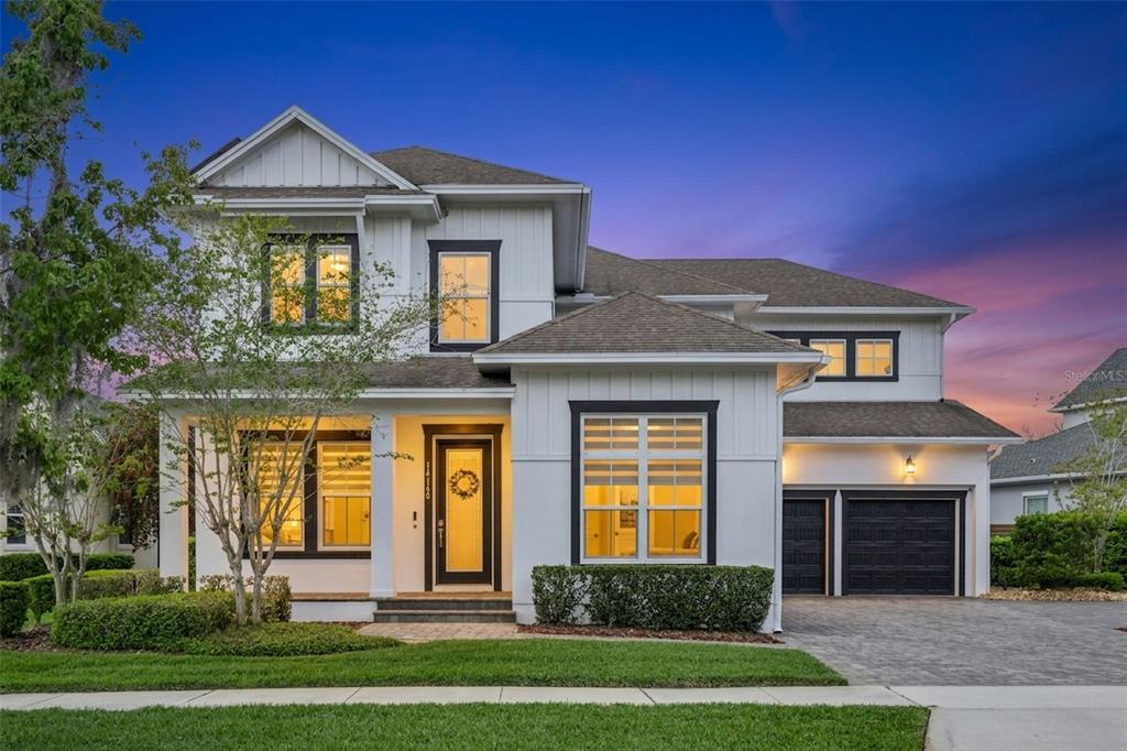 A two-story house with white vertical siding, black window frames, and a two-car garage — 14160 ELIOT AVENUE, ORLANDO, FL