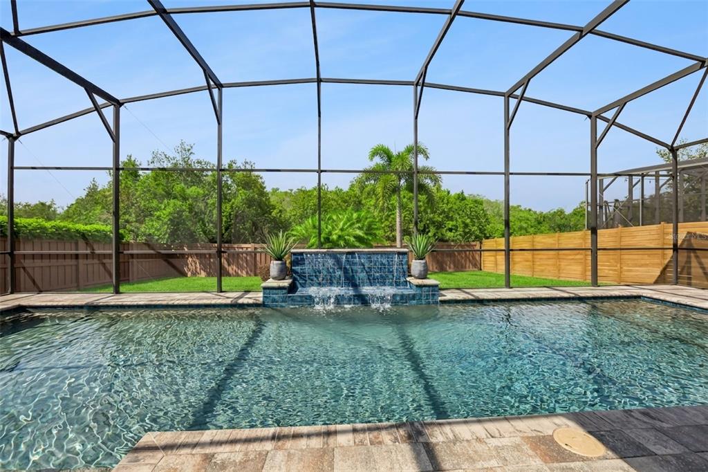 A swimming pool with a tiled water feature sits inside a screened-in patio enclosure — 14160 ELIOT AVENUE, ORLANDO, FL