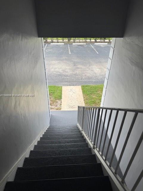 An outdoor staircase with dark treads and a metal railing leads down to a parking lot — 360 NW 69th Ave # 202, Plantation FL 33317, PLANTATION, FL