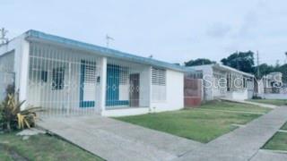 A single-story house with a white exterior, a front porch with security bars, and a lawn — 39 SIMPLICIO, JUNCOS, PR