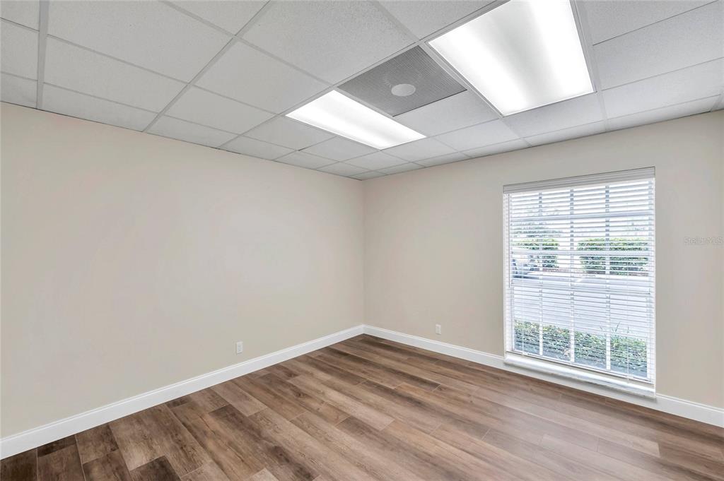 An empty office room features light-colored walls, wood-look flooring, and a drop ceiling with lights — 2401 W BAY DRIVE UNIT 410, LARGO, FL
