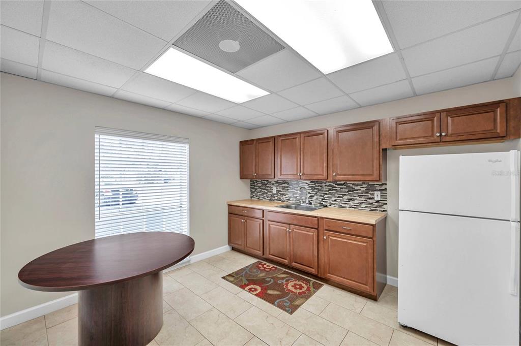 A small kitchen features wood cabinets, a white refrigerator, a sink, and a round table — 2401 W BAY DRIVE UNIT 410, LARGO, FL