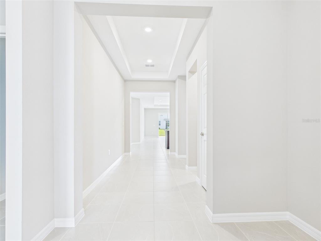 A long, white-walled hallway features a tray ceiling with recessed lighting and light-colored tile flooring — 5717 SW 71ST COURT, OCALA, FL