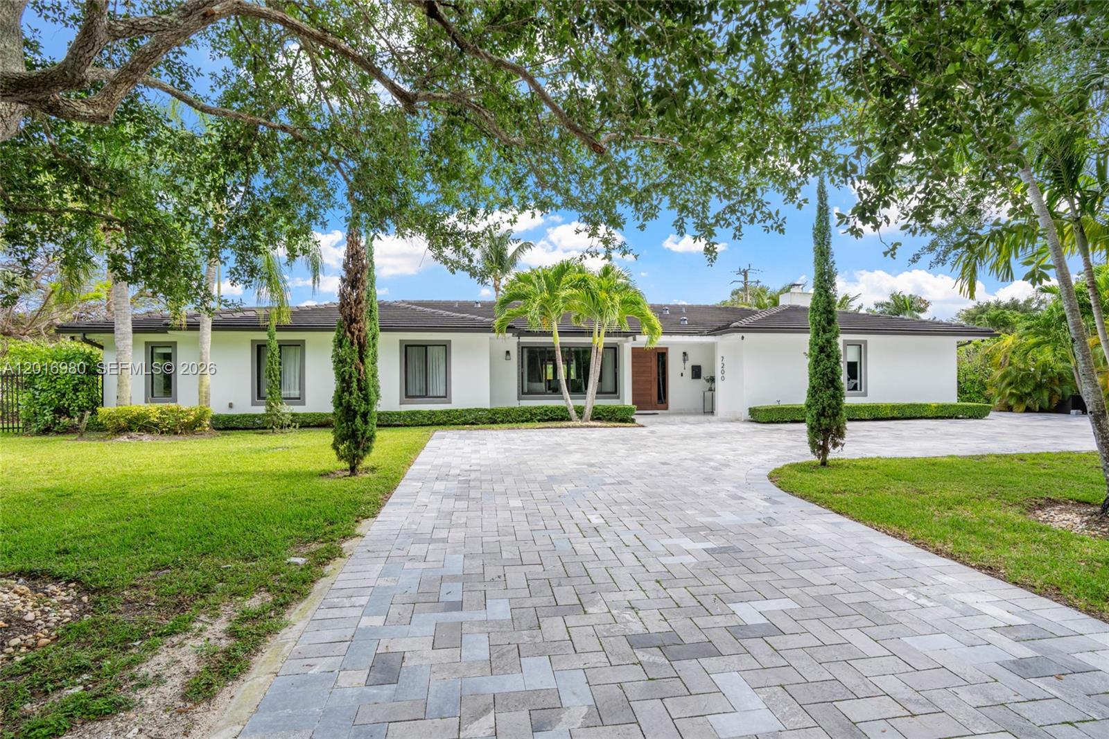 A single-story white house with a paved driveway and mature trees in the front yard — 7200 SW 107th Ter, Pinecrest FL 33156, PINECREST, FL