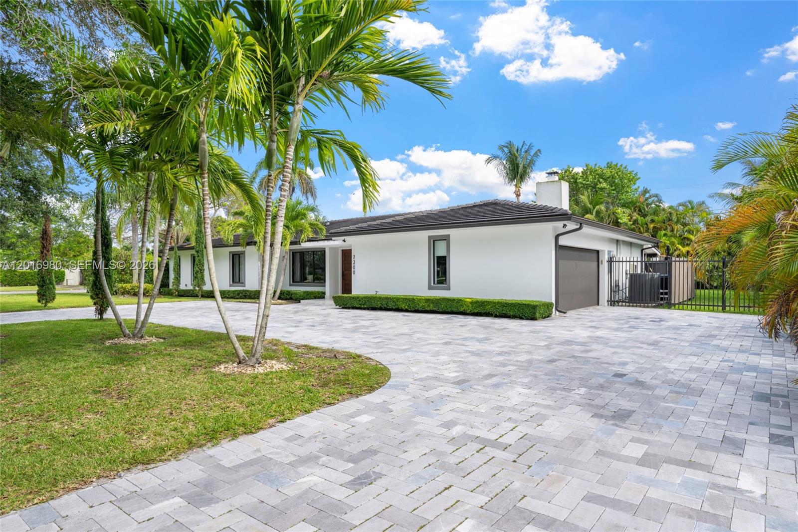 A single-story white house with a paved driveway, palm trees, and a two-car garage — 7200 SW 107th Ter, Pinecrest FL 33156, PINECREST, FL