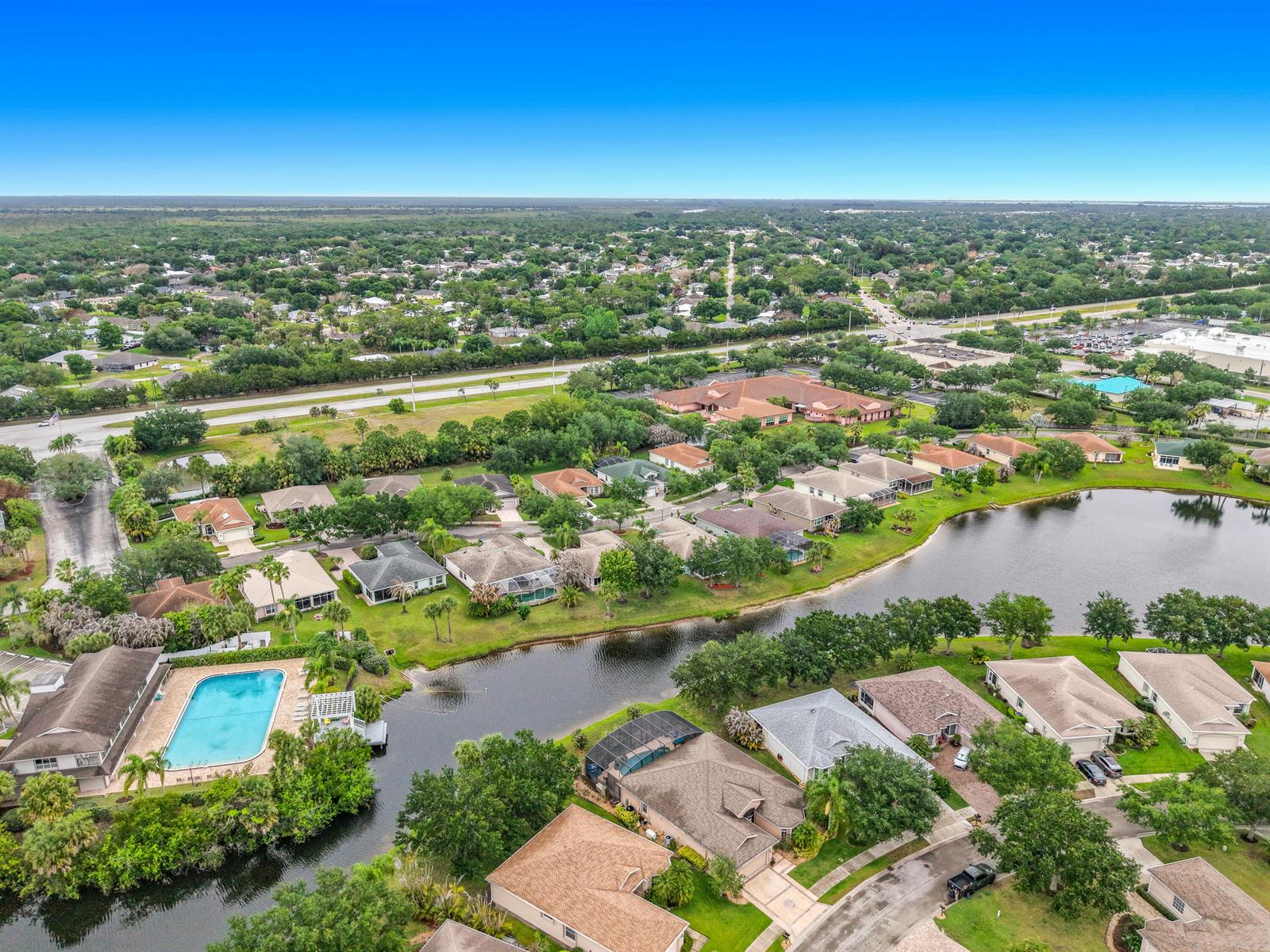 An aerial view shows a suburban neighborhood with houses, a swimming pool, and a lake — 1343 Shoreline Circle, Sebastian FL 32958, SEBASTIAN, FL