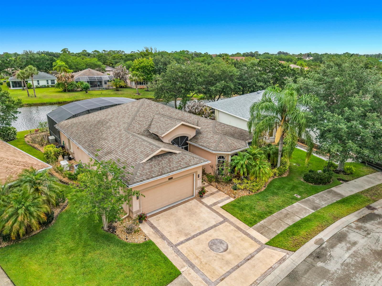 An aerial view shows a single-story house with a tan exterior, shingled roof, and pool enclosure — 1343 Shoreline Circle, Sebastian FL 32958, SEBASTIAN, FL