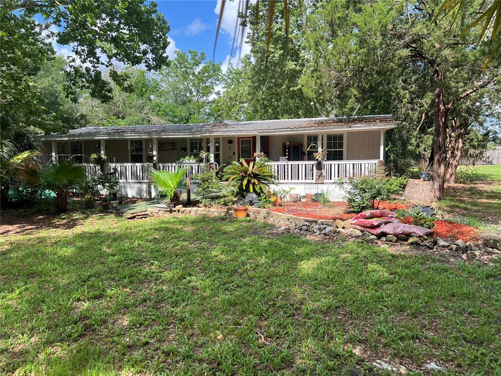 A single-story manufactured home features a long front porch and a landscaped yard — 9510 SW 94TH TERRACE, GAINESVILLE, FL