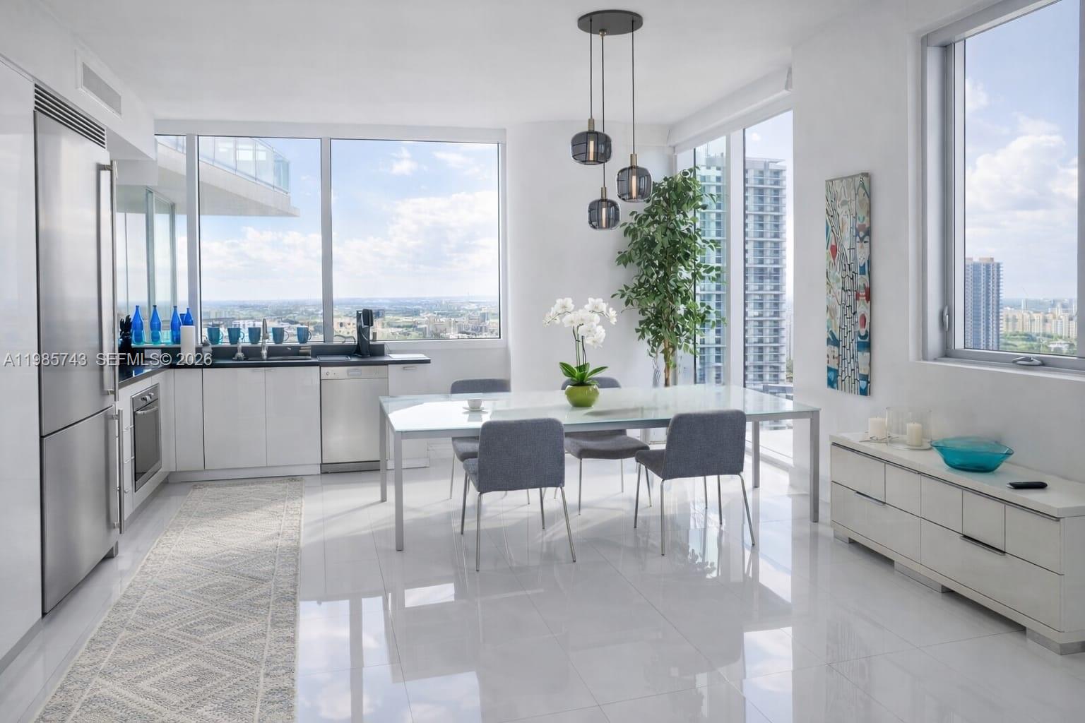 A modern dining area features a glass table, gray chairs, and floor-to-ceiling windows with city views — 92 SW 3rd St # 2510, Miami FL 33130, MIAMI, FL